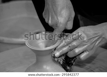 Clay potter artist making pot shape on wheel pedestal black and white version