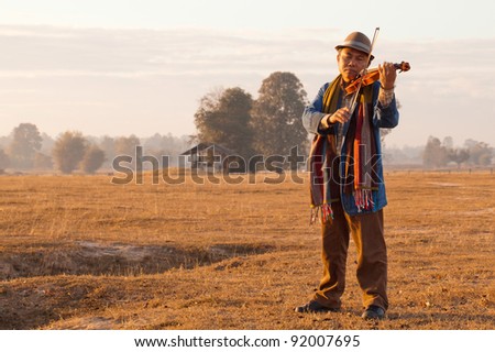 young country violinist playing his gear in last light of the day at outdoor rehearsal