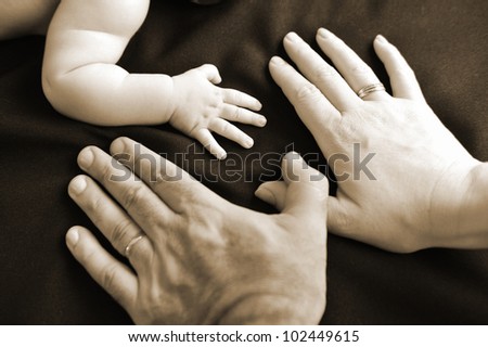 A small hand of a newborn baby compered with his parent hands.Concept photo of pregnancy, pregnant woman, newborn and baby.