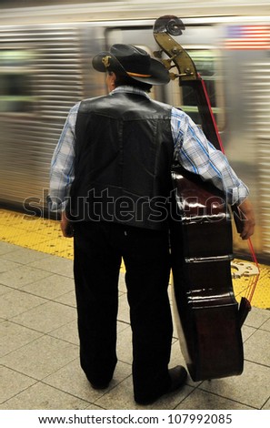 NEW YORK - OCTOBER 10 2009: An American cowboy cello player cellist carry his Cello instrument in New York subway in New York.City.It is one of the oldest public transportation systems in the world,