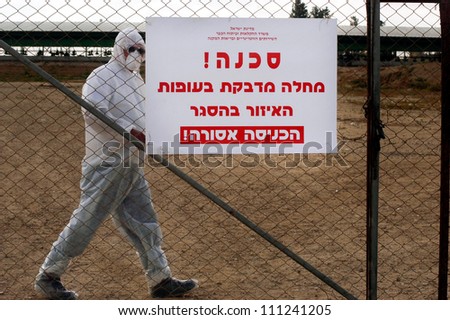 WESTERN NEGEV, ISRAEL - MARCH 17: Poultry farmer inside his turkey farm during bird flu outbreak near a warning sign in Hebrew: \