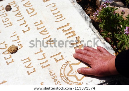 JERUSALEM - APRIL 23:A relative of a fallen soldier puts a hand on his grave at a ceremony of Memorial Day or Yom Hazikaron at the Memorial Service on Mount Herzl in Jerusalem April 23, 2007