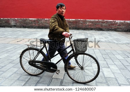 BEIJING - MARCH 11:Chinese man walk beside his bike at the Forbidden City on March 11 2009 in Beijing,China.Bicycle is the primary transportation for millions of Chinese.