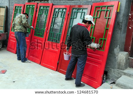 BIJING - MARCH 12:Chinese men paints old red doors in a Hutong (old neighborhood) on March 12 2009 in Beijing, China.There is around 4,000 Hutongs in Beijing some are hundreds of years old