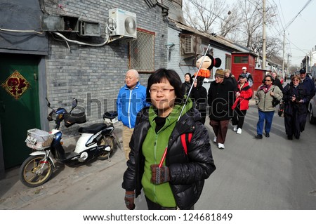 BEIJING - MARCH 11:A tour guide with tourists visiting a Hutong (old neighbourhood) on March 11 2009 in Beijing, China.There is around 4,000 Hutongs in Beijing some are hundreds of years old