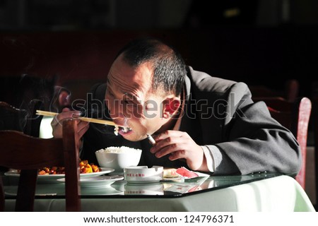BEIJING - MARCH 13 2009:Chinese man eat rice with chopsticks while eating in Beijing,China.Chinese do not like using knives and forks while eating because they believe these are weapons.