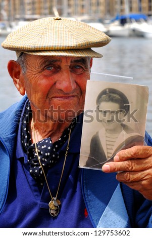 MARSEILLE - MAY 09 2008:Old French man shows his portrait as a young sailor in Marseille port, France.Worldwide, the average life expectancy is 71 years (68.5 years for males and 73.5 years for female