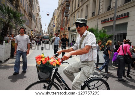 MARSEILLE - MAY 10 2008:man riding bike with basket full of fresh flowers in Marseille,France. Marseille is the oldest city in France, founded 2,600 years ago.