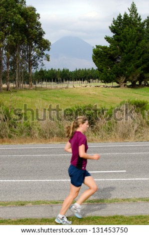 TONGARIRO, NZ - FEB 21:Young woman runs near Mt.Ngauruhoe on February 21 2013 in Tongariro National Park,New Zealand.It\'s the youngest vent of Tongariro volcanic complex, erupted about 2,500 years ago
