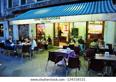 VENICE ITALY - APRIL 30 2011:People eats in a restaurant in St Mark\'s Square, Venice Italy.Each year the town receives 18 million tourists. This equates to approximately 50,000 visitors each day
