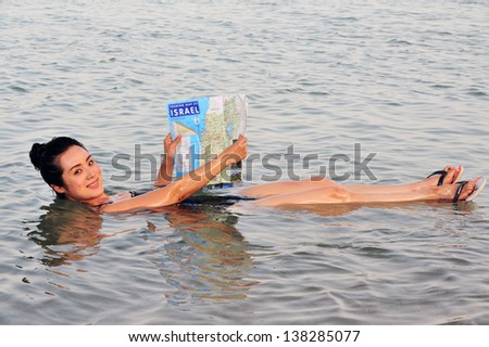 DEAD SEA- MAY 14:A young Chinese woman floats while reading a map of Israel on May 14 2010.It\'s the second saltiest body of water in the world, with a salt content of 33% .