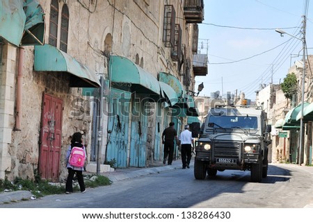 HEBRON, ISRAEL - SEP 08:Israeli IDF Jeep pass by arab people in Hebron on September 09 2009.There are 163,000 Palestinians living in Hebron