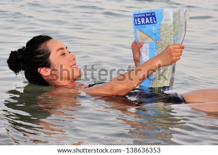 DEAD SEA, ISR - MAY 14:A young Chinese woman floats while reading a map of Israel on May 14 2010.It\'s the second saltiest body of water in the world, with a salt content of 33%.