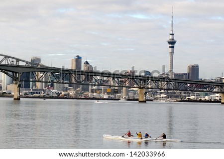 AUCKLAND, NZ - JUNE 02:Crew of a racing outrigger canoe training against Auckland skyline on June 02 2013.It become a very popular paddling sport with numerous sporting clubs located around the world.