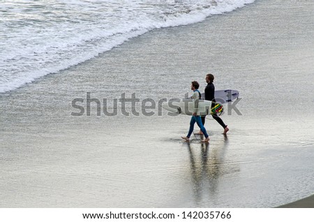 PIHA, NZ - JUNE 01:Two young wave surfers in Piha beach near Auckland on June 01 2013.According to the International Surfing Association the estimate number of surfers worldwide is 23 million.