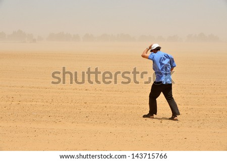 NIRIM,ISR - JUNE 22:Man fights a sand storm on June 22 2010.Dust storms increase the spread of disease across the globe when ground virus blown into the atmosphere acting like urban smog or acid rain.