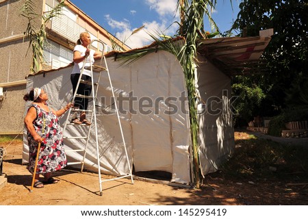 SDEROT, ISR - OCT 10:Israeli women build a sukkah on Oct 10 2008.The sukkah has at least three sides, a roof is made out of branches that provides shade from the sun, but also lets you see the stars.