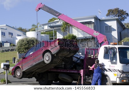CABLE BAY,NZ - JULY 01:Man towing damaged car over a tow truck on July 01 2013.Many tow companies have the capability to store vehicles that have been wrecked or impounded by police agencies.