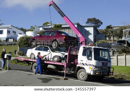 CABLE BAY,NZ - JULY 01:Man towing damaged car over a tow truck on July 01 2013.The tow truck was invented in 1916 by Ernest Holmes,of Chattanooga, Tennessee.