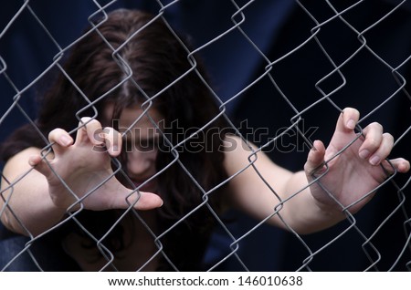 A missing kidnapped, abused, hostage, victim girl alone in emotional stress and pain, afraid, restricted, trapped, call for help, struggle, terrified, threaten, locked in a cage cell try to escape.