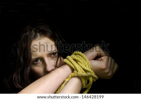 Missing kidnapped, abused, hostage, victim woman with hands tied up with rope in emotional stress and pain, afraid, restricted, trapped, call for help, struggle, terrified, locked in a cage cell.