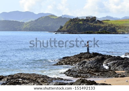 CABLE BAY,NZ- AUG 22:Mature man fishing from a rock on Aug 22 2013.New Zealand exclusive economic zone covers 4.1 million square kilometers and It\'s the sixth largest zone in the world.