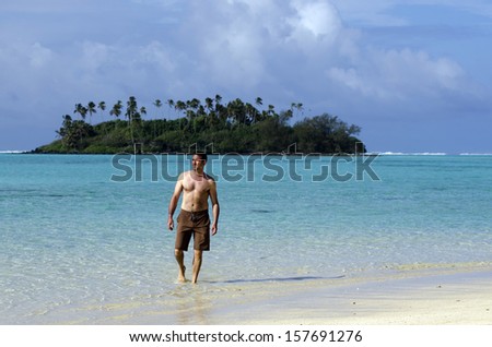Man walks out of the water of a Pacific Island.Concept photo of men travel and tourism. survival, alone, deserted Island, castaway.