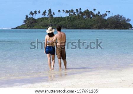 Attractive young happy couple on vacation looks at small Pacific Island. Concept photo of couples travel ,tourism, love, relationship, honeymoon.