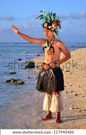 Portrait of attractive young Polynesian Pacific Island Tahitian male dancer in colorful costume dancing on tropical beach during sunset.