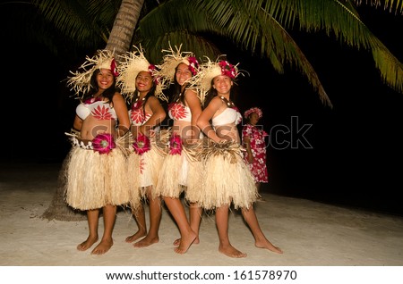Portrait of young Polynesian Pacific Island Tahitian women dancers in colorful costume dancing on tropical beach.