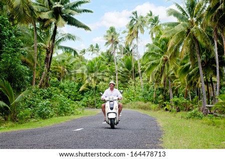 AITUTAKI - SEP 20:Tourist man drives hired motorbike on Sep 20 2013.It\'s one of the must popular activity in the Island but Cook Islands Driver\'s License is required to operate a motorized rental.