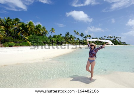 Young woman relaxing on a deserted tropical island in Aitutaki Lagoon, Cook Islands