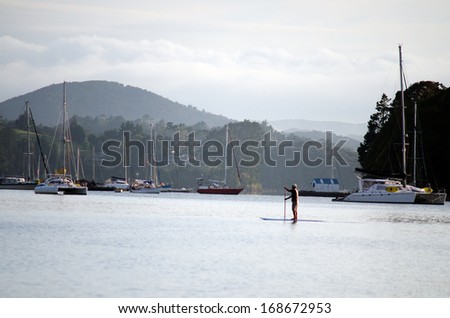 BAY OF ISLANDS, NZ - DEC 12: Man Stand up paddle surfing on Dec 12 2013.It's an emerging global sport with a Hawaiian heritage.It's an ancient form of surfing for longer distances.