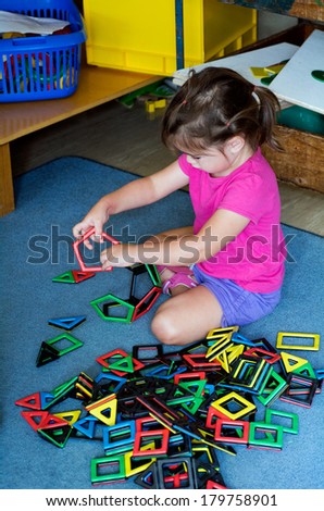 Little girl play with building toy in a play room. Concept photo of preschool education of creativity and thinking