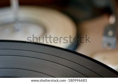 Gramophone vinyl record against old record player in the background. Concept photo of retro music and sound