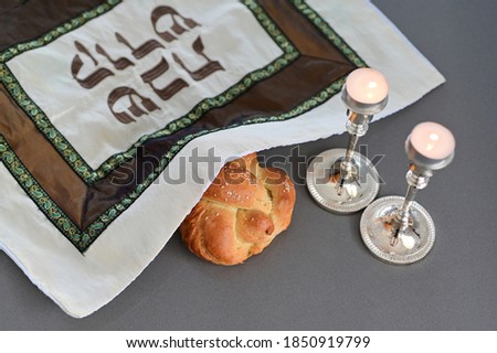 Challah (Jewish bread) with cover  with Hebrew text reading 'Holy Sabbath' beside two lit candles on Sabbath eve Jewish Holiday (Judaism's day of rest on the seventh day of the week - Saturday) Foto stock © 