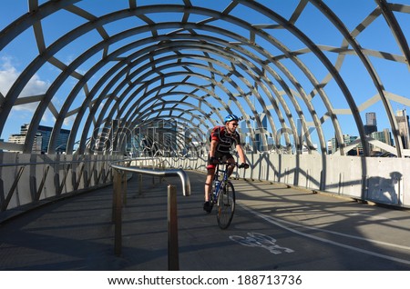 MELBOURNE,AUS - APR 14 2014:Cyclist cross on Webb Bridge.It\'s an award winning bridge forming a cycling and pedestrian link to the main part of Docklands, through Docklands Park.