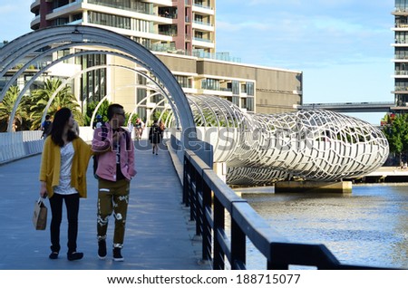 MELBOURNE,AUS - APR 14 2014:Visitors cross on Webb Bridge.It\'s an award winning bridge forming a cycling and pedestrian link to the main part of Docklands, through Docklands Park.