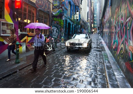 MELBOURNE, AUS - APR 10 2014: Pedestrians and a car pass at Hosier Lane.Hosier lane is a much celebrated landmark in Melbourne mainly due to its sophisticated graffiti urban art.