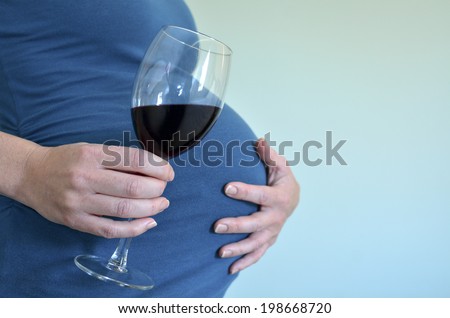 Pregnant woman drinks alcohol (red wine) during pregnancy .Concept photo of pregnancy, pregnant woman lifestyle and health care. crop image - copyspace