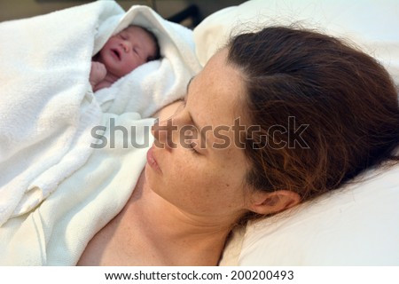 Mother with her newborn baby in bed immediately after natural water birth labour. Concept photo of  pregnant woman, newborn, baby, pregnancy.