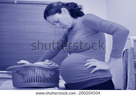 Pregnant housewife woman doing housework, washing family clothes, during pregnancy.Concept photo of pregnancy, pregnant woman lifestyle and health care. crop image - copyspace (BW)