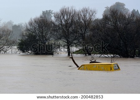 KAWAKAWA , NZL -JUNE10 2014:Submerge car in a flooded road near a river in Northland.Floods are the most frequent and costly natural disasters in New Zealand
