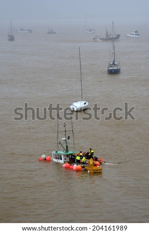MANGONUI, NZL - JULY 10 2014:Rescue team try to save a sinking boat.High winds lashing the upper North Island of New Zealand have sank boats, blown roofs off houses and cut power to thousands.
