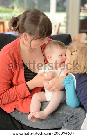 Happy young mother play with her baby and child at home. Concept photo of newborn, baby, mother, motherhood, parenting and lifestyle