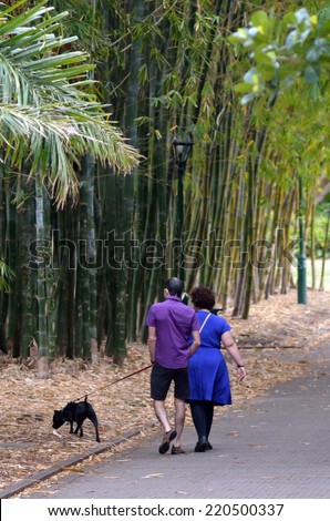 BRISBANE, AUS - SEP 24 2014:Couple walking a dog at Brisbane City Botanic Gardens.The Gardens include many rare and unusual botanic species of plants, flowers and trees.