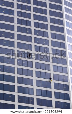 BRISBANE - SEP 25 2014:Window cleaners works on high rise building.Window cleaning is considered one of the most dangerous job in the world.Several window cleaners die each year and many are injured