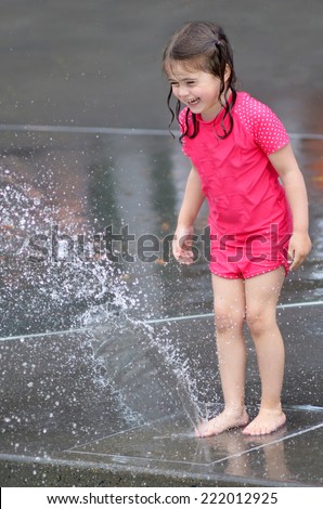 Child (girl age 04) play with water fountain. concept photo hot weather and heatwave. copyspace