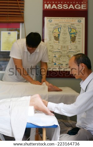 GOLD COAST - SEP 30 2014:Asian therapists gives foot massage.Archaeological evidence of massage has been found in many ancient civilizations including China, India, Egypt, Rome, Greece and Mesopotamia