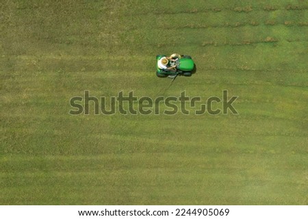Aerial drone landscape view of Australian man riding ride on lawn mower cutting green grass. Real people. Copy space Foto stock © 